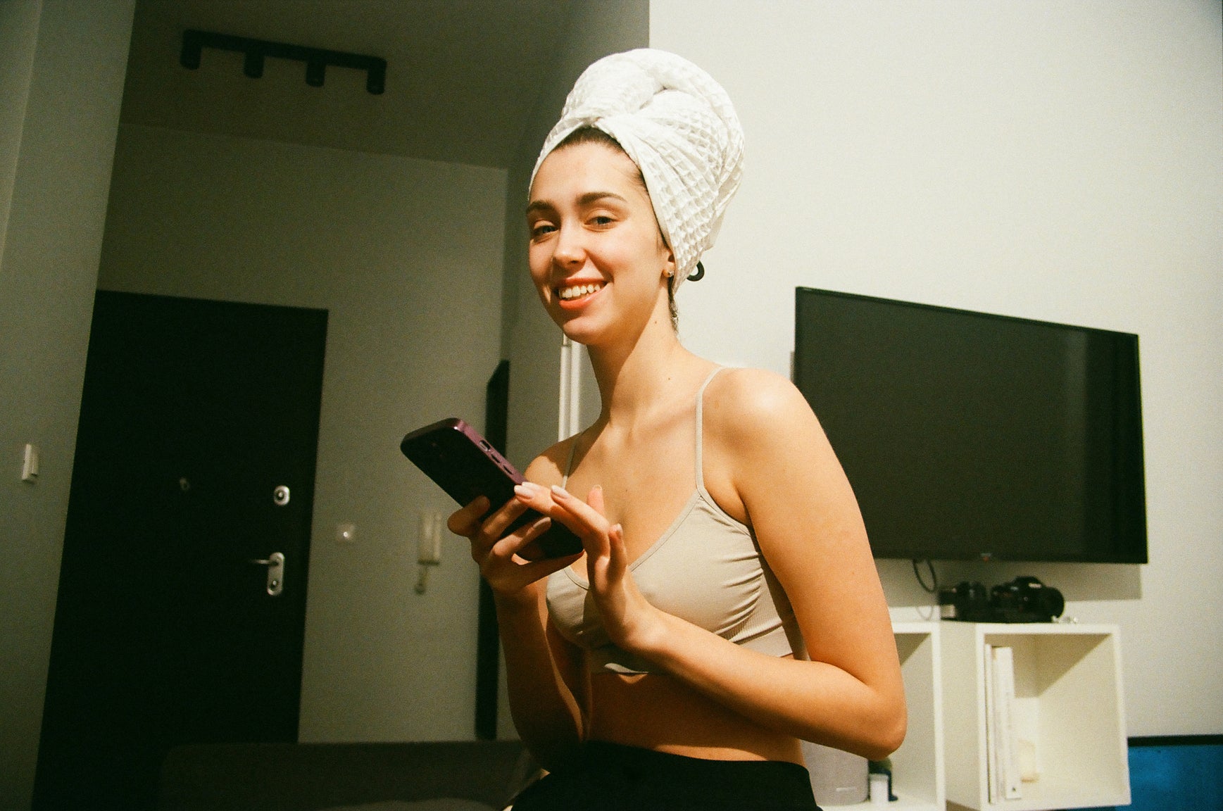 Femme chez elle avec les cheveux dans une serviette et prenant son telephone